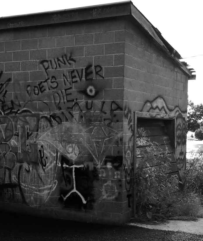 image of a graffitti covered wall, text on wall says punk poets never die